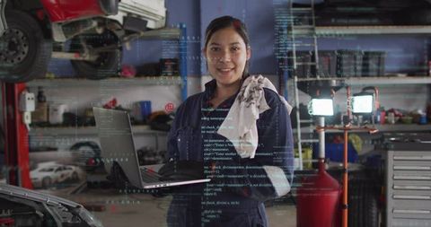 Woman mechanic holding laptop running digital vehicle diagnostics in auto repair garage