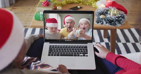 Family Celebrating Christmas Over Video Call Wearing Santa Hats and Unwrapping Ornament