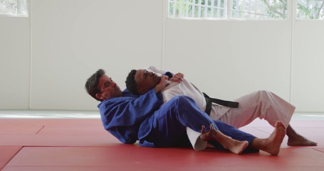 Two men in judo gi engaging in a practice session on red mat. Perfect for sports training materials, martial arts promotions, fitness blogs, and educational content about judo techniques and physical conditioning.