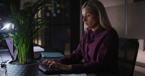 Focused Businesswoman Typing on Keyboard in Late Night Office