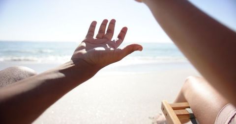 Relaxing vacation scene with arm extended on sunny beach
