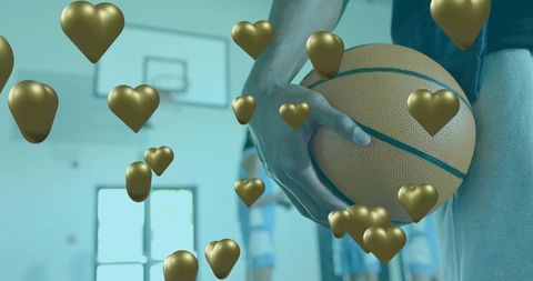 Male athlete holding basketball with floating gold heart balloons in teal gym atmosphere