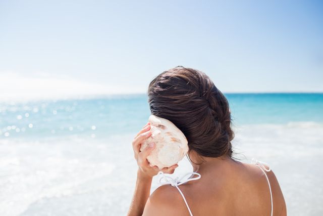 Woman Listening to Seashell on Sunny Beach - Download Free Stock Photos Pikwizard.com