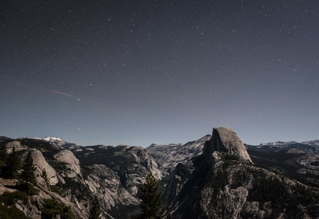 Starry night sky above Yosemite National Park mountains, focusing on natural beauty and serenity of Half Dome and surrounding wilderness. Ideal for travel blogs, environmental campaigns, adventure tourism promotions, nature-themed prints, desktop wallpapers.