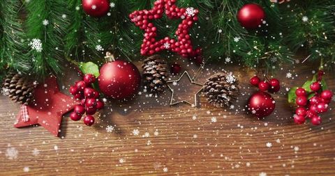 Rustic christmas garland with red baubles, pine cones and star ornaments on wood