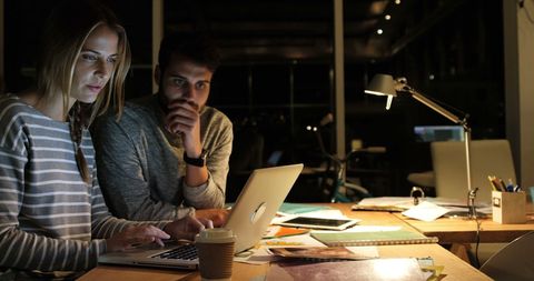 Young Professionals Collaborating on Laptop in Dimly Lit Office - Download Free Stock Images Pikwizard.com