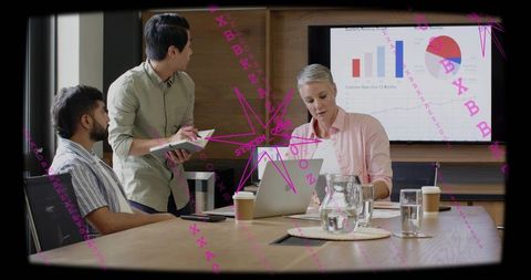 Mature executive leading collaborative meeting with laptop and charts in modern boardroom