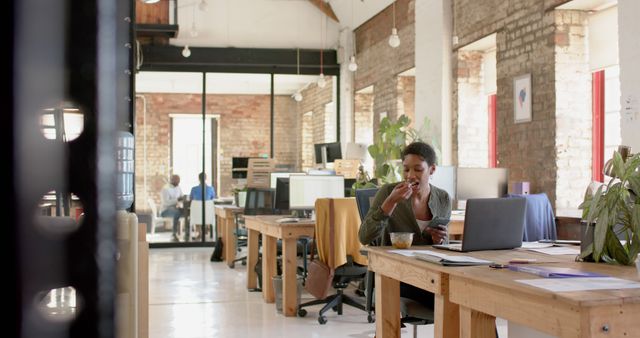 Businesswoman Eating Snack While Working in Modern Loft Office - Download Free Stock Images Pikwizard.com