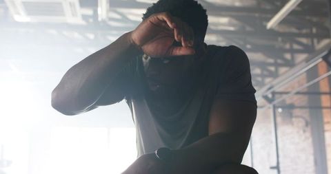 Determined athlete wiping sweat in industrial warehouse gym