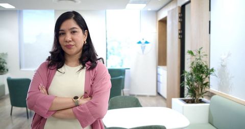 Confident woman standing with arms crossed in modern clinic waiting area