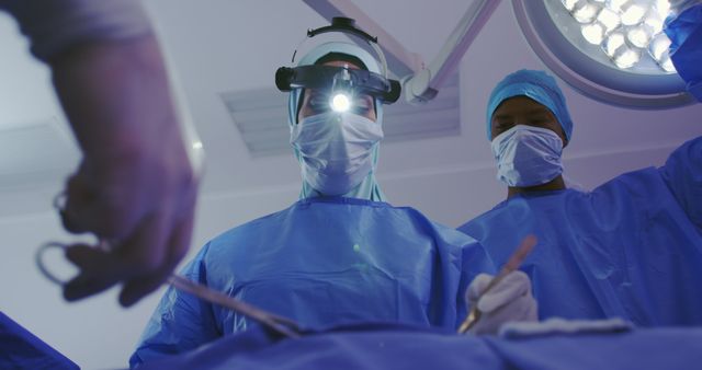 Low angle view of Middle-east female surgeon performing surgery in operation theater at hospital. She is holding surgical instruments
