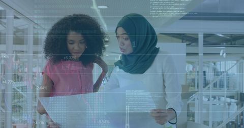 Diverse Businesswomen Discussing Financial Data with Digital Interface Overlay