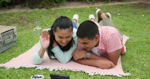 Young Couple Lounging Outdoors Watching Smartphone