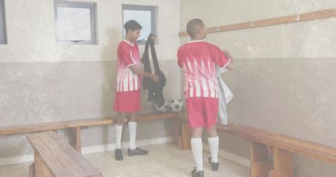 Youth soccer players preparing in locker room holding kit bag and ball
