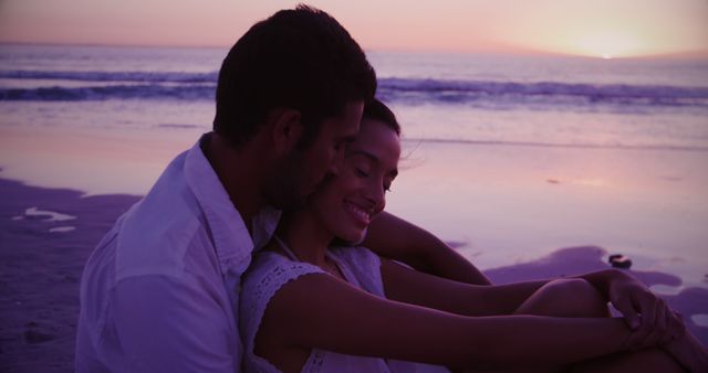 Biracial couple enjoys a beach sunset, with copy space. They share a romantic moment by the sea at dusk.