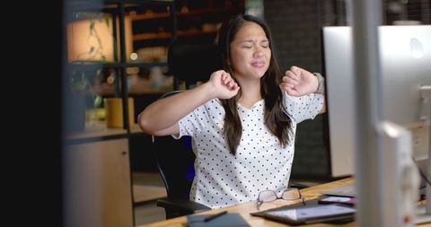 Tired businesswoman stretching at office desk