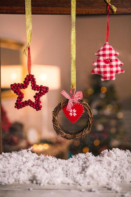 This festive image showcases a close-up of a grapevine wreath hanging on a snowy window, accompanied by a red star and Christmas tree ornaments. The scene emits a cozy and warm holiday atmosphere, perfect for Christmas cards, holiday marketing, festive blog posts, and seasonal social media content.