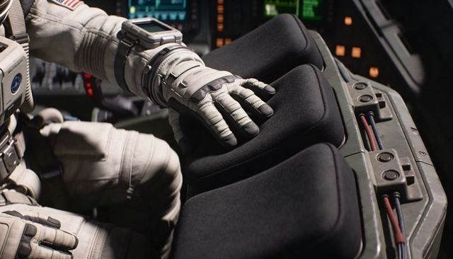 Spacesuited astronaut resting hand on triple cushioned armrests inside spacecraft cockpit