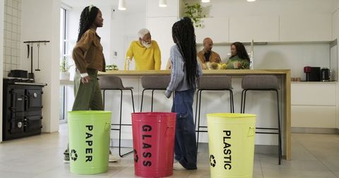 Multigenerational Family Sorting Recycling in Modern Kitchen with Paper Glass Plastic Bins