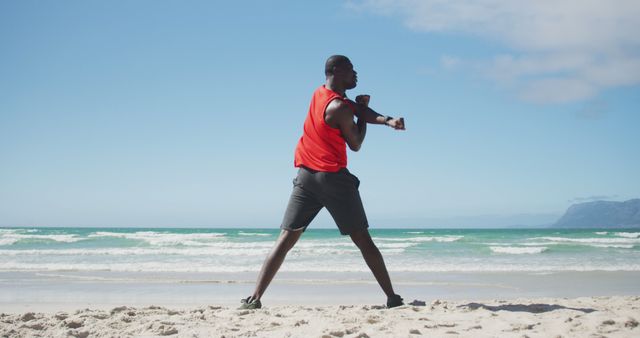 African american man stretching on the beach, exercising outdoors by the sea - Download Free Stock Photos Pikwizard.com