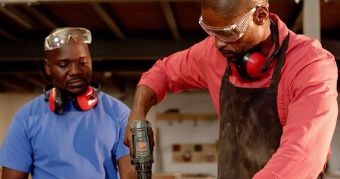 African american coworkers drilling wood at workshop