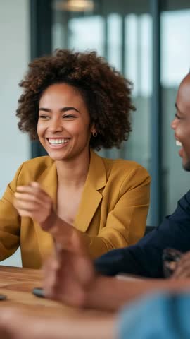 Vertical video: Laughing woman in mustard blazer clapping during team meeting