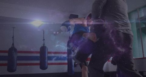 Athlete delivering jumping kick during pad training in gym with cosmic light overlay