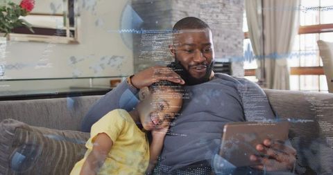 Father and daughter bonding on couch with tablet and augmented reality overlays