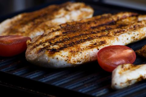Grilled seasoned chicken breast with charred grill marks and tomato halves