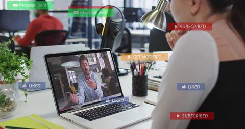 Remote team video conference in modern open office with employee watching presenter on laptop