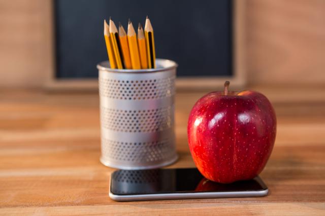 Red Apple on Mobile Phone Next to Pencils in Classroom - Download Free Stock Photos Pikwizard.com