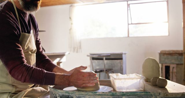 Potter shaping clay on spinning wheel in bright studio - Download Free Stock Images Pikwizard.com