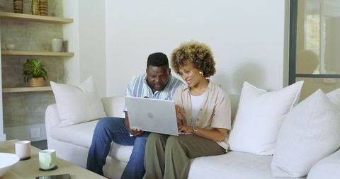 African American Couple Relaxing with Laptop on Modern Sofa