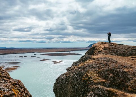 Hiker capturing majestic river views from cliff top