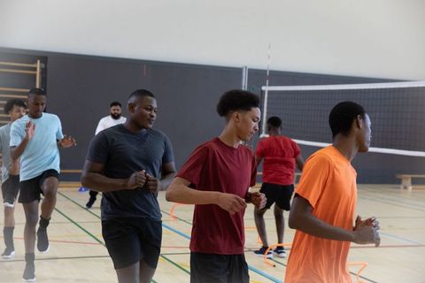 Youth athletes running agility drills in indoor gymnasium during team training session