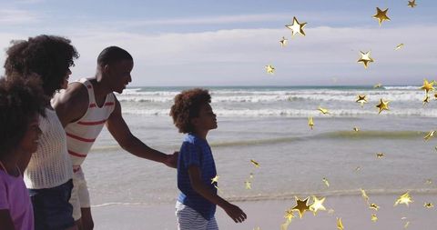 Happy family strolling on sunny beach with golden stars