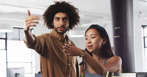 Diverse colleagues collaborating and communicating at desk in modern office