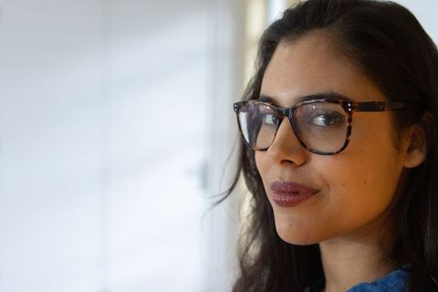 Confident woman wearing tortoiseshell eyeglasses and blue top, natural closeup headshot