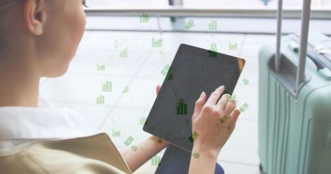 Business traveler using tablet at airport tapping data dashboard analytics next to luggage