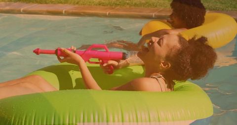 Playful Woman Enjoying Backyard Pool with Water Gun Fun