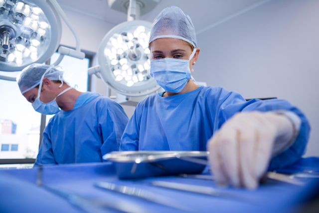 Female surgeon selecting surgical tools in operation theater at hospital
