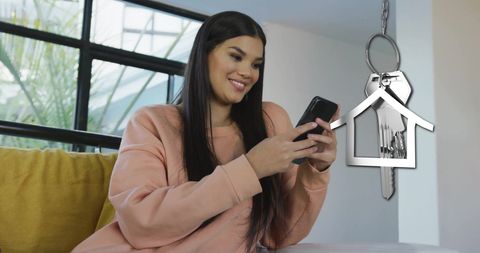 Happy Woman on Smartphone with House Key Symbolizing Home Ownership