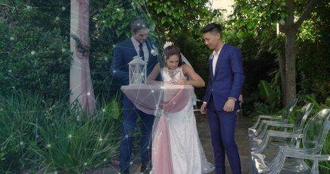 Bride signing marriage certificate at outdoor garden table while groom and witness watch