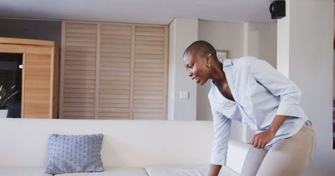 Smiling woman entering modern living room with cozy sofa
