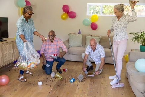 Diverse Senior Friends Cleaning After Celebratory Gathering in Living Room