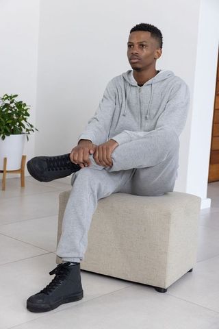 African american man relaxing at home in grey hoodie and black sneakers