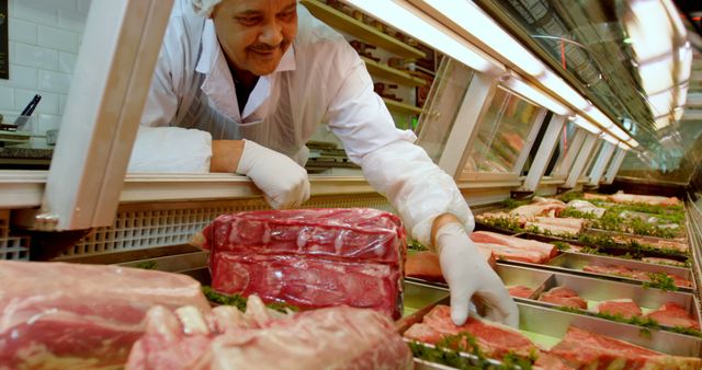 Butcher arranging fresh meat cuts in market display case - Download Free Stock Images Pikwizard.com