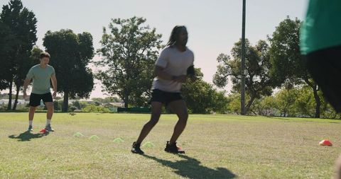Male athlete leading teammates through agility cone drill and hurdle acceleration training