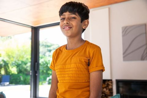 Smiling indian boy in contemporary home with orange t-shirt