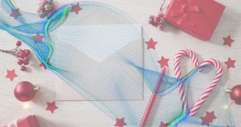 Draping iridescent mesh ribbon over cream envelope with candy cane heart flatlay holiday